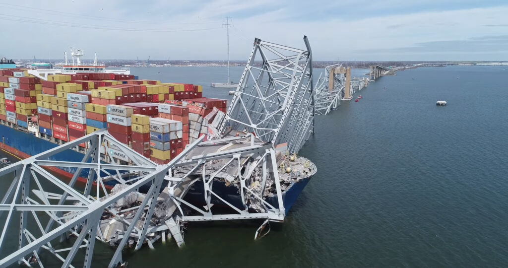 An image showing the collapsed Key Bridge in Baltimore, with a container ship lodged in its suspension cables.