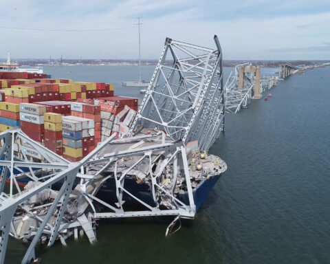 An image showing the collapsed Key Bridge in Baltimore, with a container ship lodged in its suspension cables.